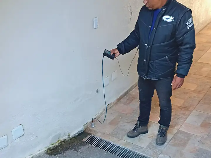 Técnico de fone de ouvido varrendo o piso com o geofone em área externa